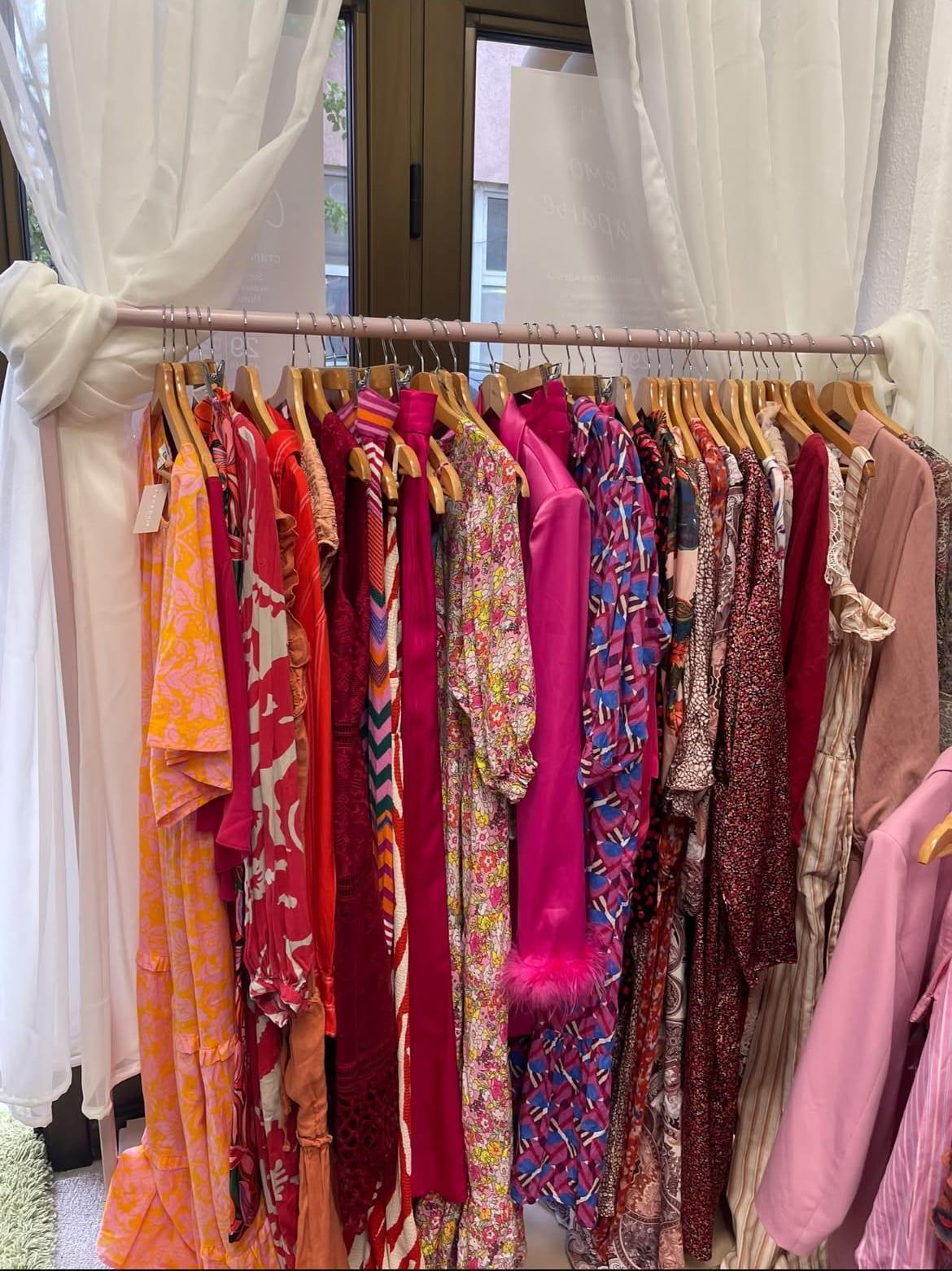 A rack of pre-loved clothing by a sunlit window at the galerija boutique.